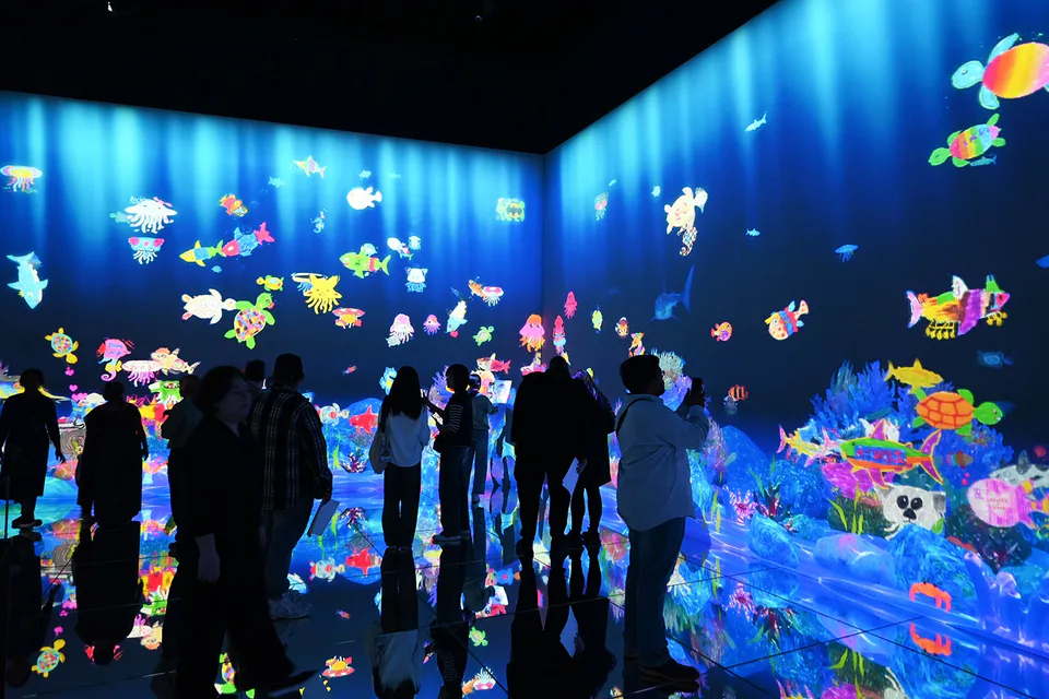 ผู้เข้าชมวาดภาพสิ่งมีชีวิตในทะเลที่เคลื่อนไหวในทะเลดิจิทัลของ teamLab Borderless Sketch Ocean