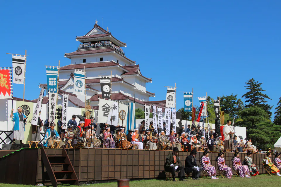 เวทีงานเทศกาลอิวะจิหน้าปราสาททสึรุกะและธงของขุนนางในแต่ละยุค จะแสดงบรรยากาศประวัติศาสตร์ของอิวะจิ
